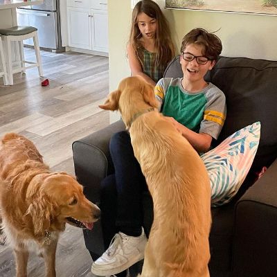 Picture of Brecken Merrill and his younger sister, Karis Merrill, and their two golden retrievers.